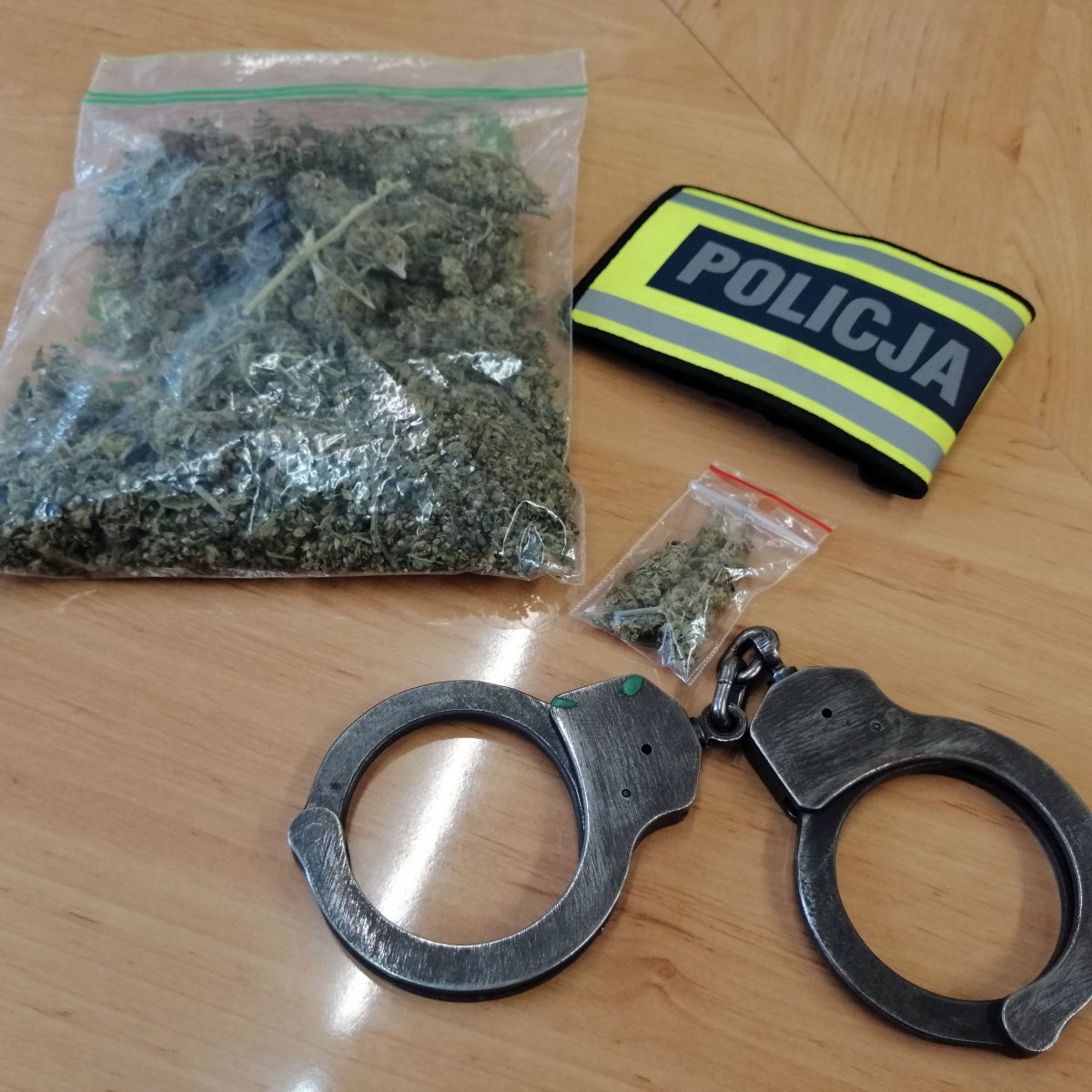 worek duży i mały z marihuaną, kajdanki i opaska z napisem Policja