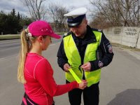 policjant wręcza kobiecie odblaskowe opaski