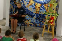 policjantka siedzi i czyta bajkę dzieciom