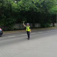 policjant tarczą drogową daje sygnał do zatrzymania się