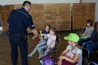 policjant wręcza dzieciom opaski odblaskowe
