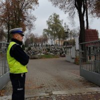 policjant stoi przy bramie cmentarza