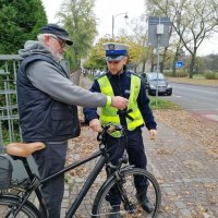 policjant zakłada rowerzyście odblask