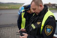 policjant i strażnik miejski oglądają zapis obrazu na wyświetlaczu z drona
