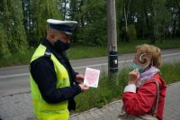 policjant wręcza kobiecie laurkę i odblask