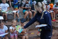 policjantka rozdaje kolorowanki dzieciom