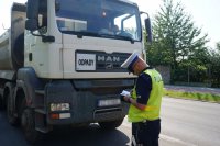 policjant z drogówki stoi przed ciężarówką z napisem odpady