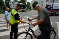 policjant wręcza opaskę odblaskową rowerzyście