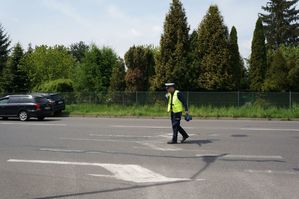 na zdjęciu policjant na drodze daje sygnał tarczą do zjechania pojazdowi